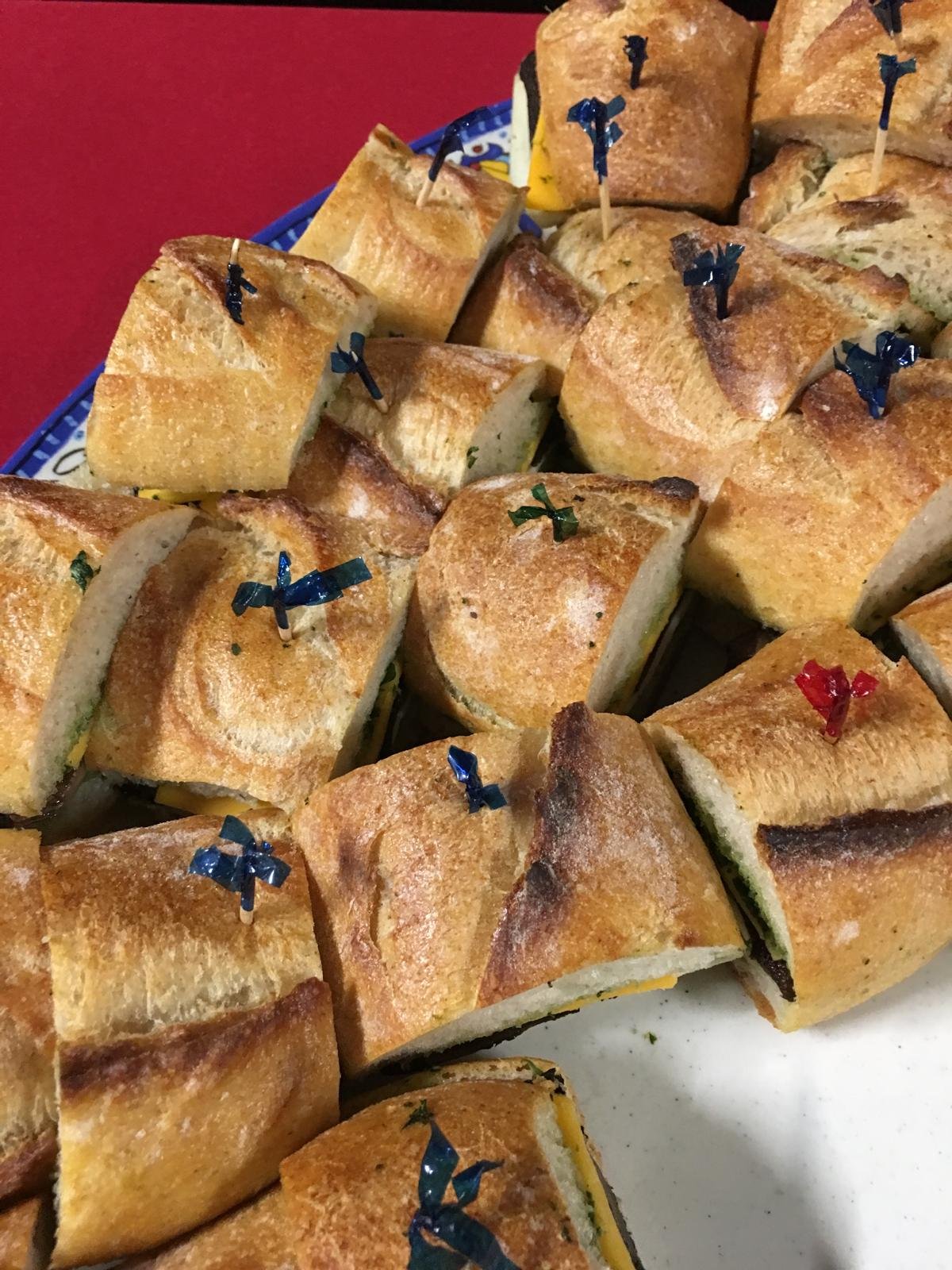 Baguette sandwich squares with picks on a platter.