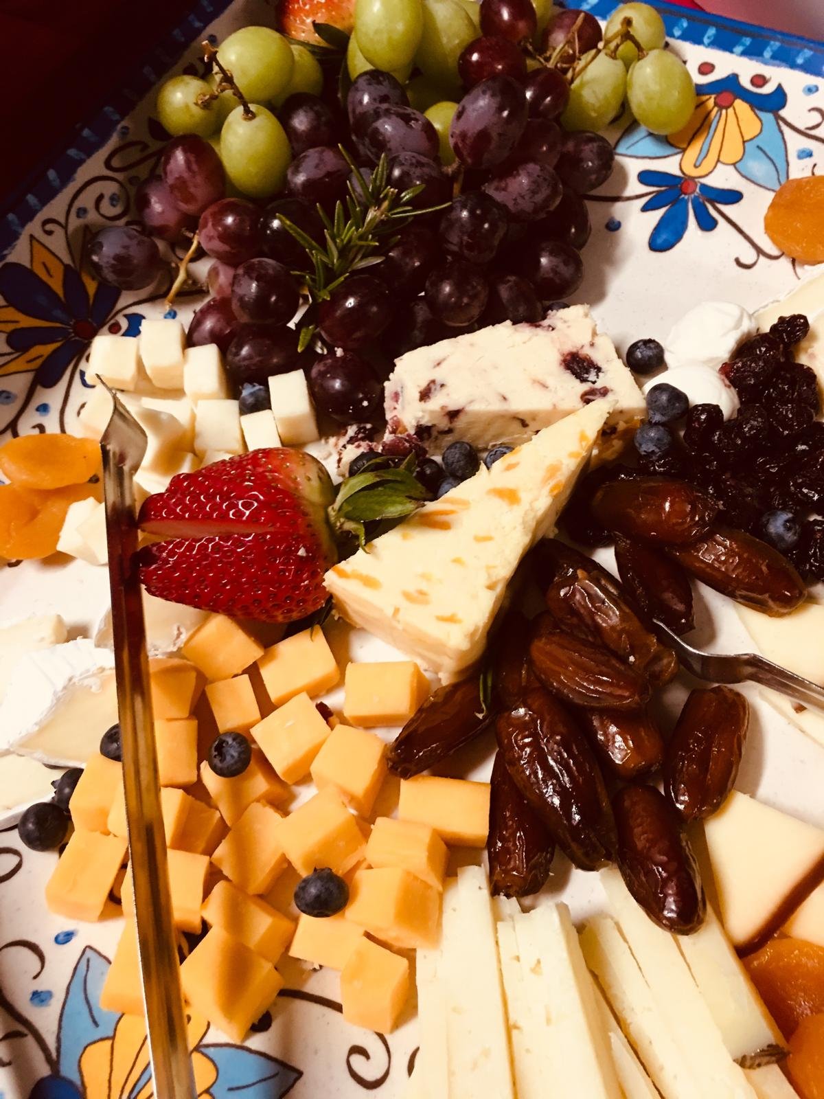 A cheese board with dates, strawberries and blueberries.