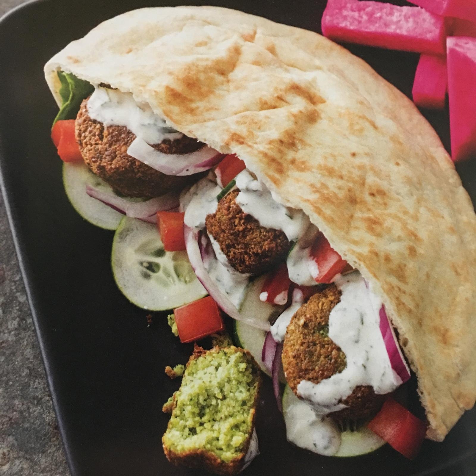 A falafel pita with cucumber, tomato and yogurt sauce.