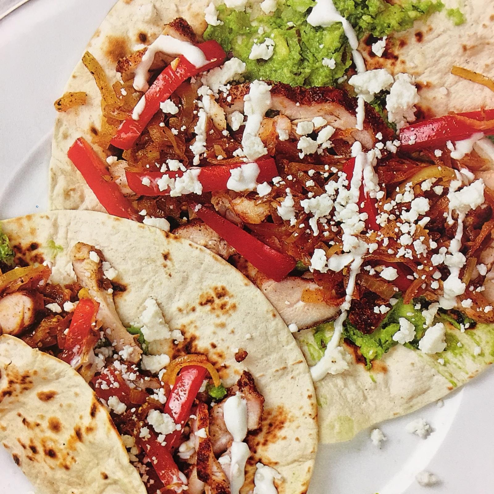 Chicken tacos topped with peppers and crumbled feta.