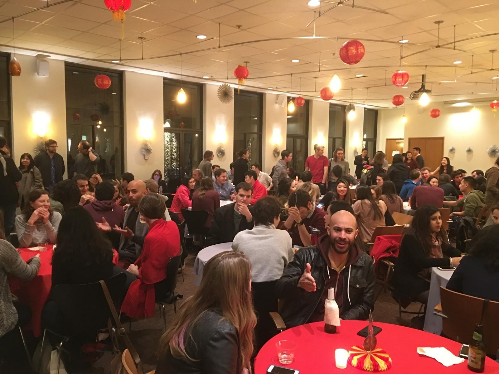 A full banquet room at lunch, dozens of people at round tables under red lanterns.