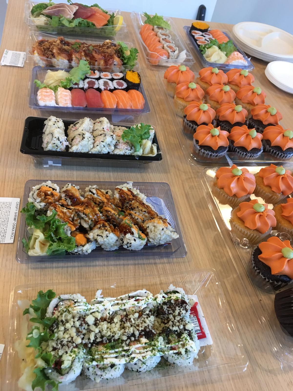 Salmon rolls, a topped roll platter and pumpkin-frosted cupcakes on a table.